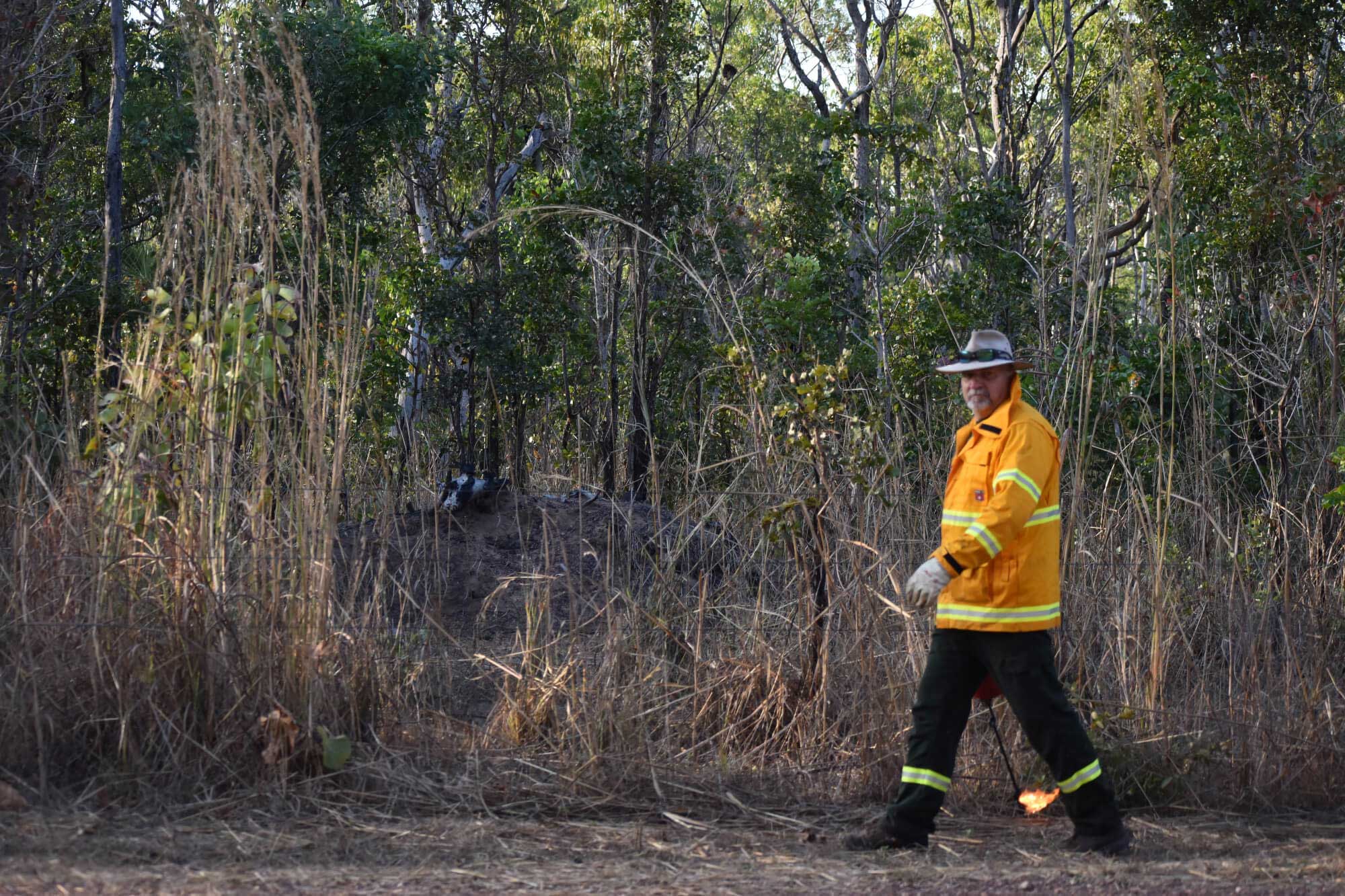 Firefighter walking in front of dry bushes