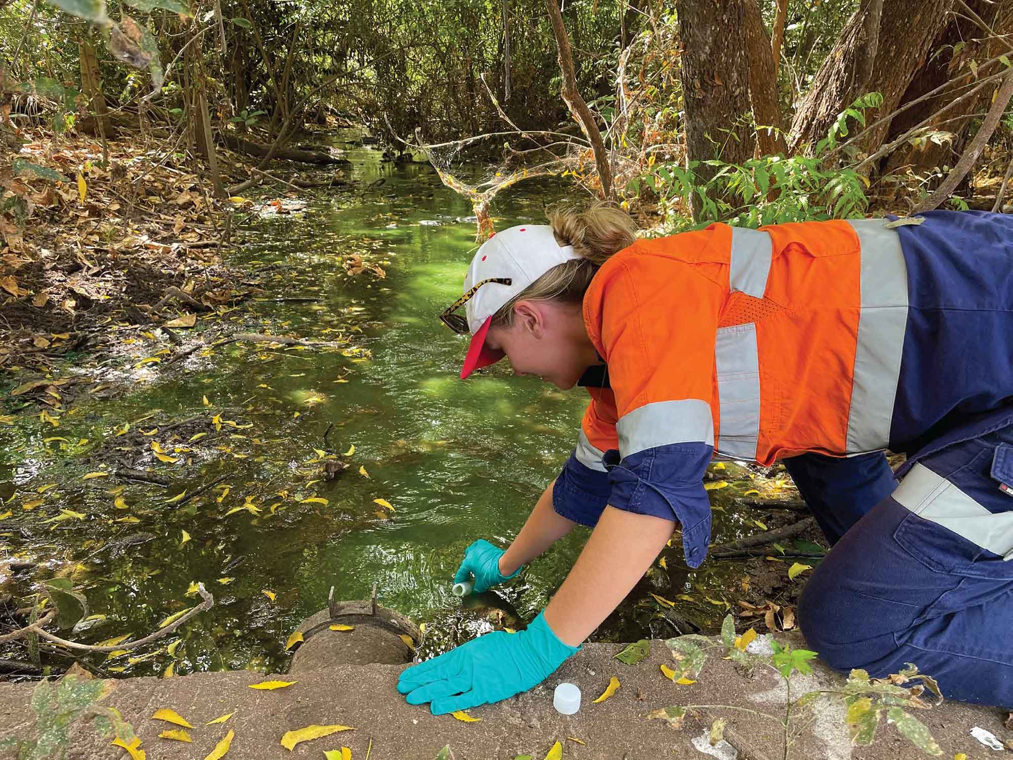 Worker sampling water from a body of water.